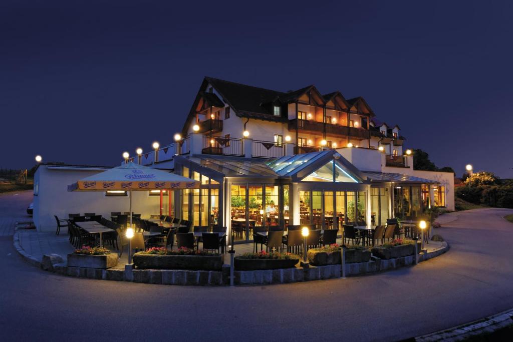 诺因布尔格福尔姆瓦尔德湖滨全景酒店的一座大建筑,晚上有桌子和遮阳伞
