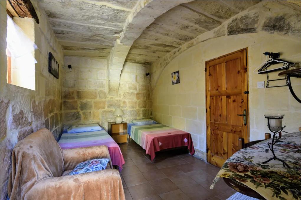 沙拉400YR Farmhouse in Xaghra Gozo - Separate Rooms的一间设有两张床、一张沙发和一扇门的房间