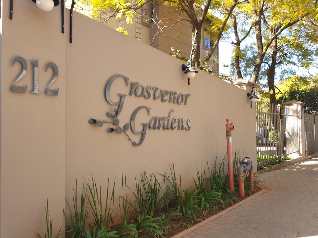 比勒陀利亚Grosvenor Apartments的建筑边的标志,带有消防栓