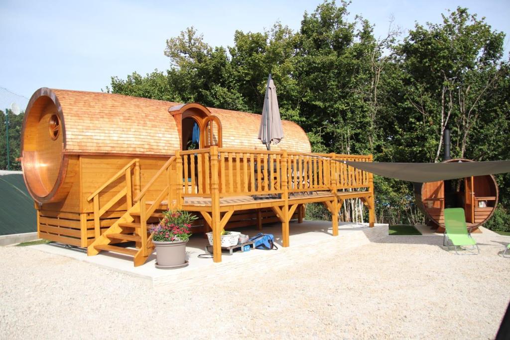 Dompierre-sur-MontL'Insolite Jurassienne的大型木屋设有甲板和遮阳伞