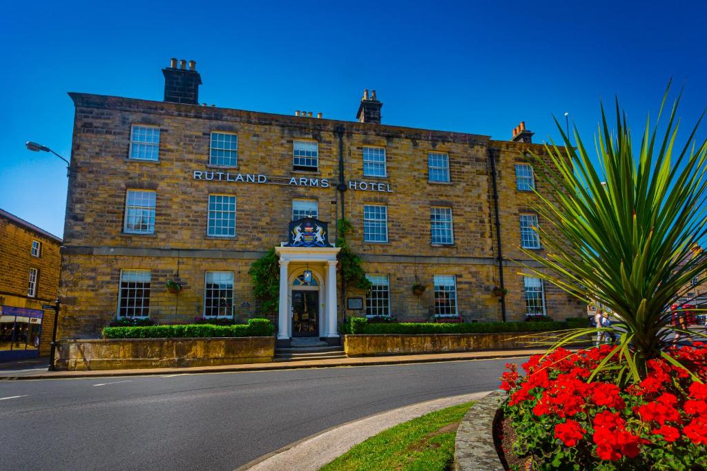 贝克韦尔The Rutland Arms Hotel, Bakewell, Derbyshire的前方有钟的大砖砌建筑