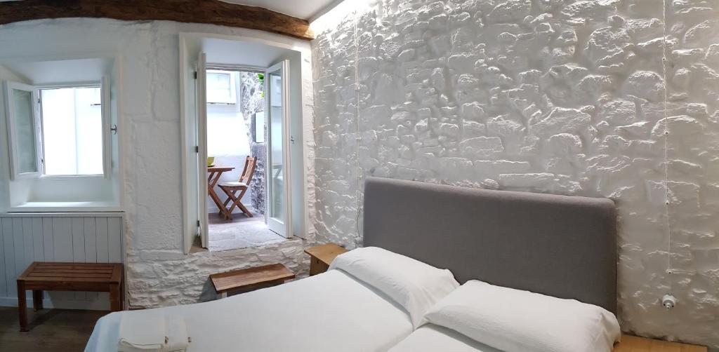 圣地亚哥－德孔波斯特拉迷人的圣马蒂诺旅馆的一间卧室设有石墙和床