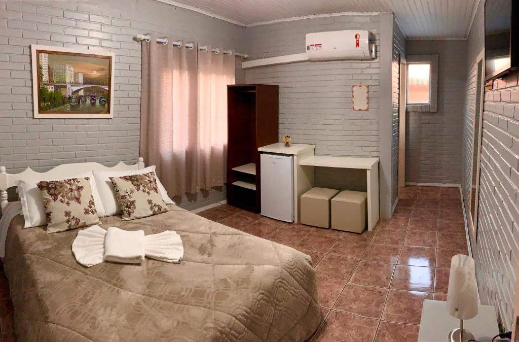 卡内拉Pousada Bello Outono的一间卧室配有一张大床和一台小冰箱