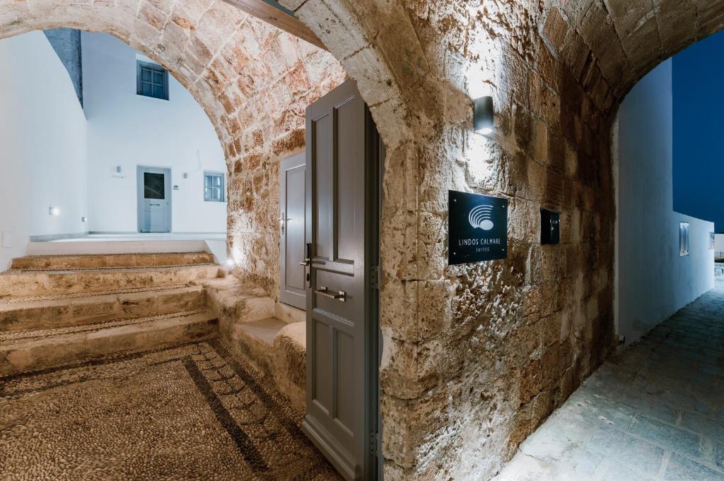 林都斯Lindos Calmare Suites的石墙中带开放式门的走廊