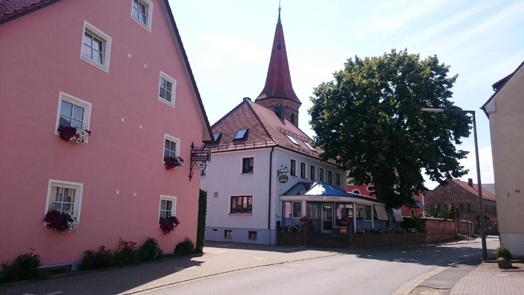 阿勒斯贝格Gasthof Endres的教堂旁的粉红色建筑,有陡峭的陡峭
