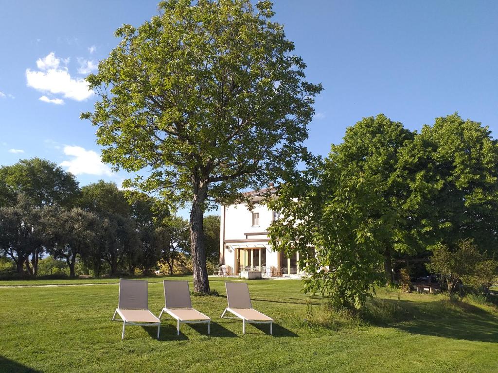蒙赞巴诺Agriturismo Olistico Atman的坐在房子前面的草上,有三把椅子