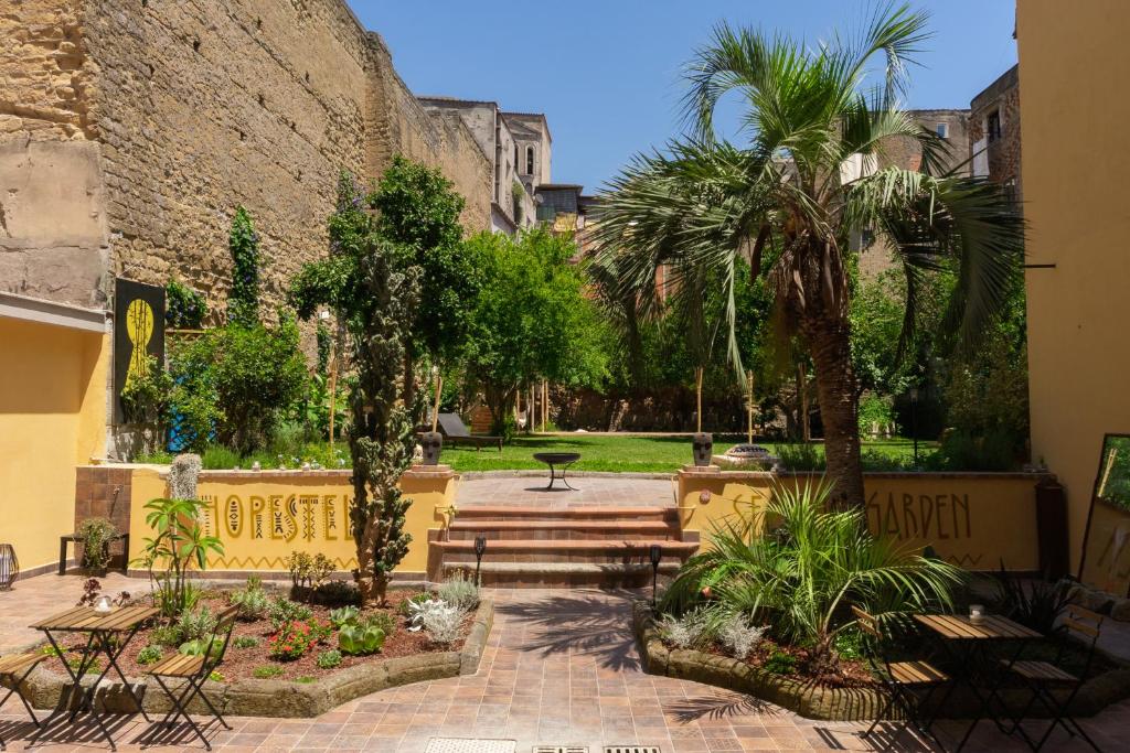 那不勒斯HOPESTEL Secret Garden Napoli的一个带棕榈树和石墙的庭院