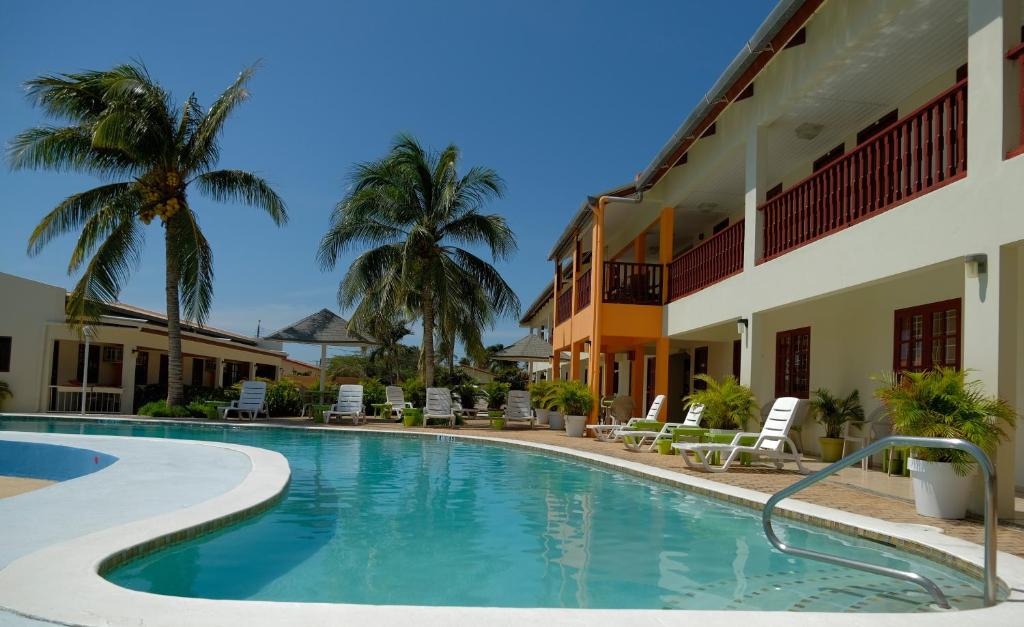 棕榈滩Aruba Quality Apartments & Suites的棕榈树酒店前的游泳池