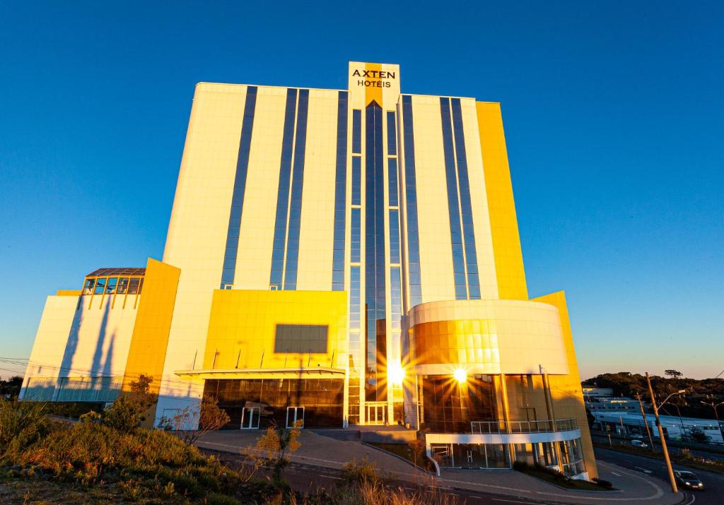 南卡希亚斯Travel Inn Axten Caxias do Sul的一座黄色和白色的大建筑,上面有阳光
