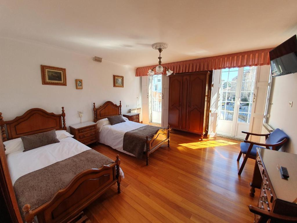 圣地亚哥－德孔波斯特拉吉亚达斯旅馆的一间卧室设有两张床和大窗户