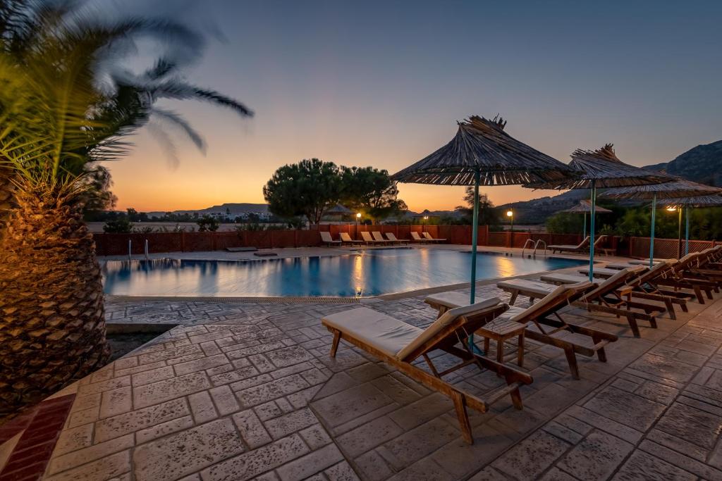 卡尔扎迈纳卡利梅拉马雷酒店的一组椅子和遮阳伞,位于游泳池旁
