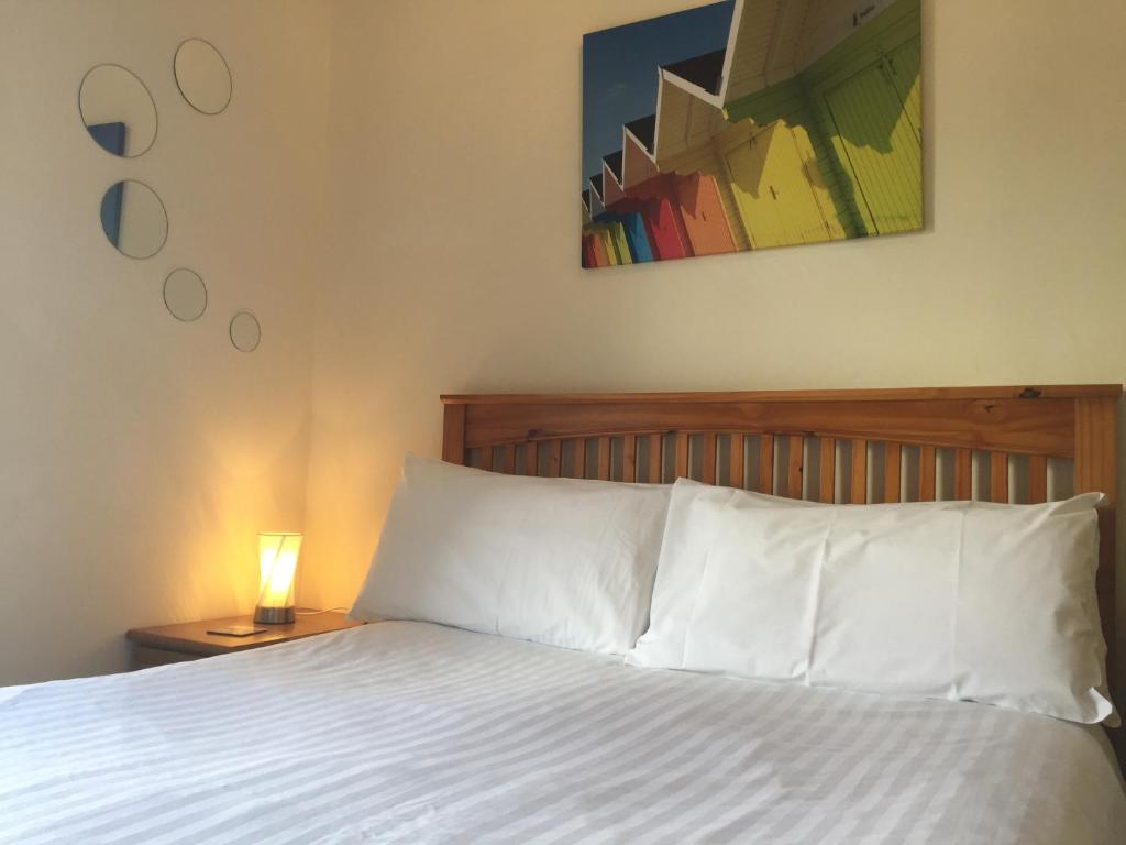 普里茅斯Barbican Reach Guest House的一张带白色床单的床和一张桌子上的台灯