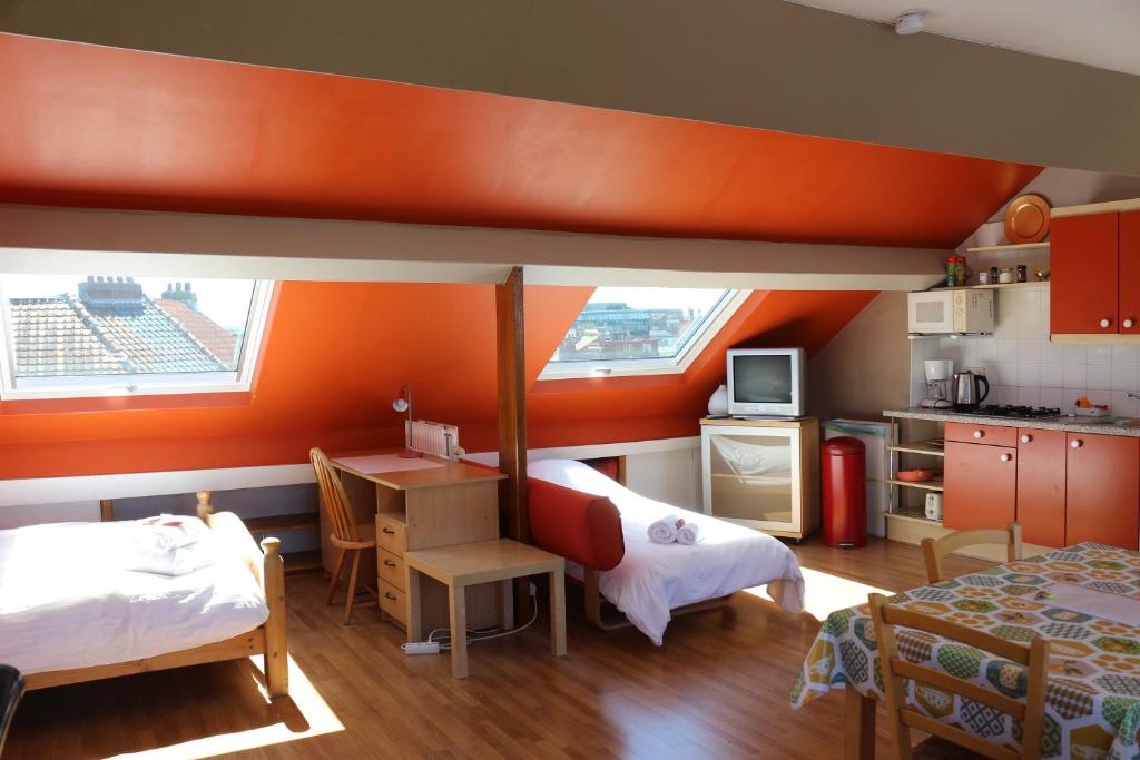 布鲁塞尔布鲁塞尔住宿加早餐酒店的带两张床的房间和带橙色墙壁的厨房