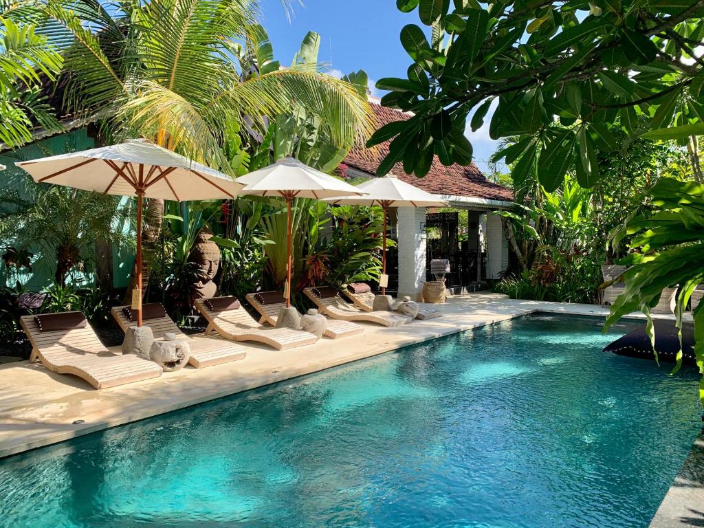 乌鲁瓦图Hari Indah Boutique Hotel & Spa的度假村内带椅子和遮阳伞的游泳池