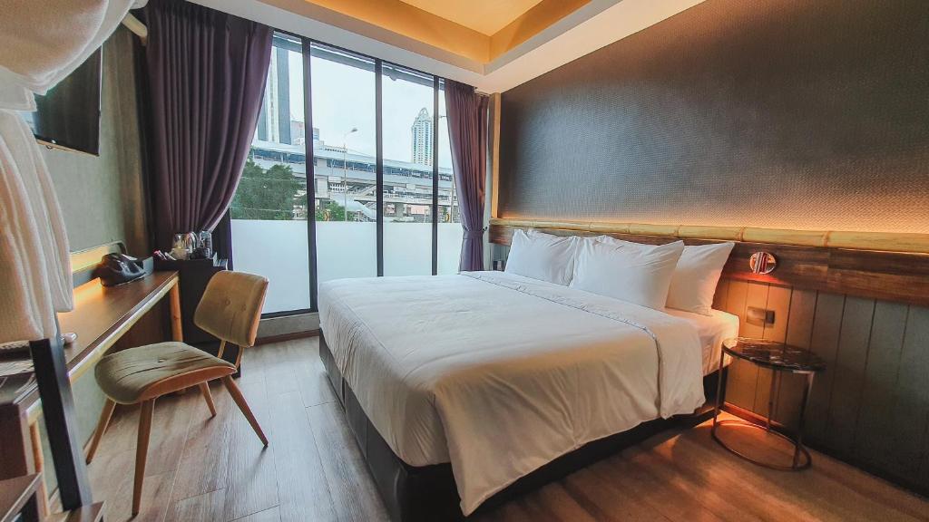 曼谷Hotel Ordinary Bangkok的酒店客房设有一张床和一个大窗户
