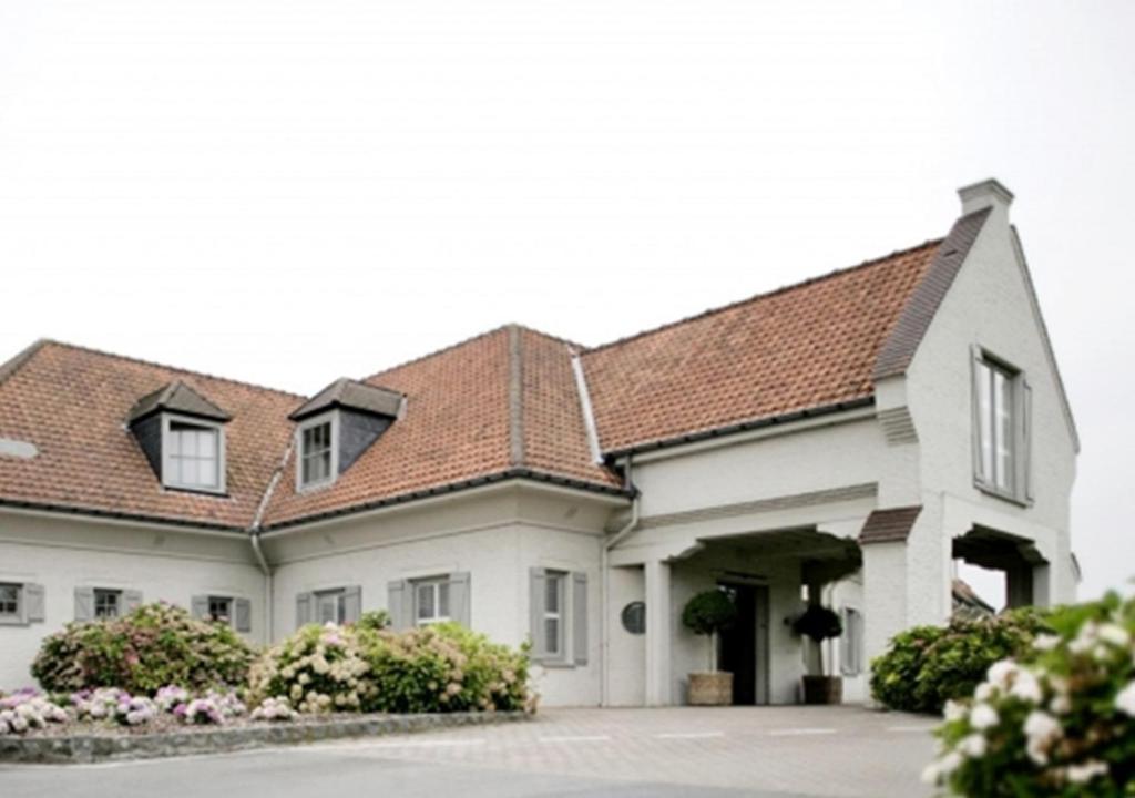 科特赖克Hostellerie Klokhof的一间白色的大房子,有棕色的屋顶