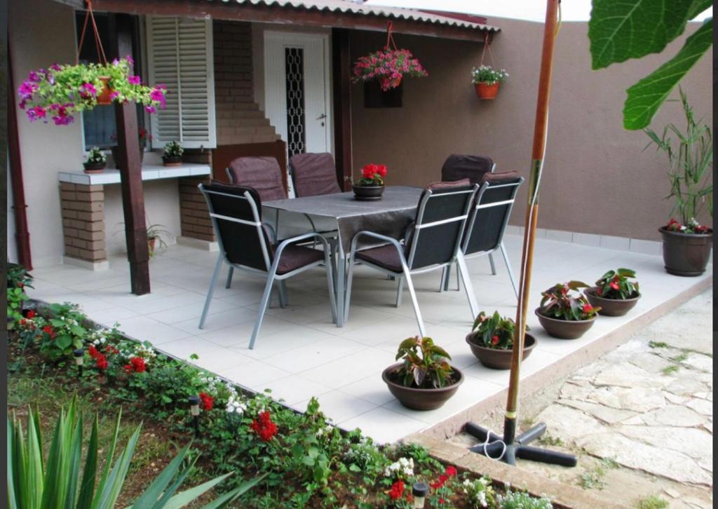 佩罗杰Apartman Andja sea and garden view的天井配有桌椅和盆栽植物