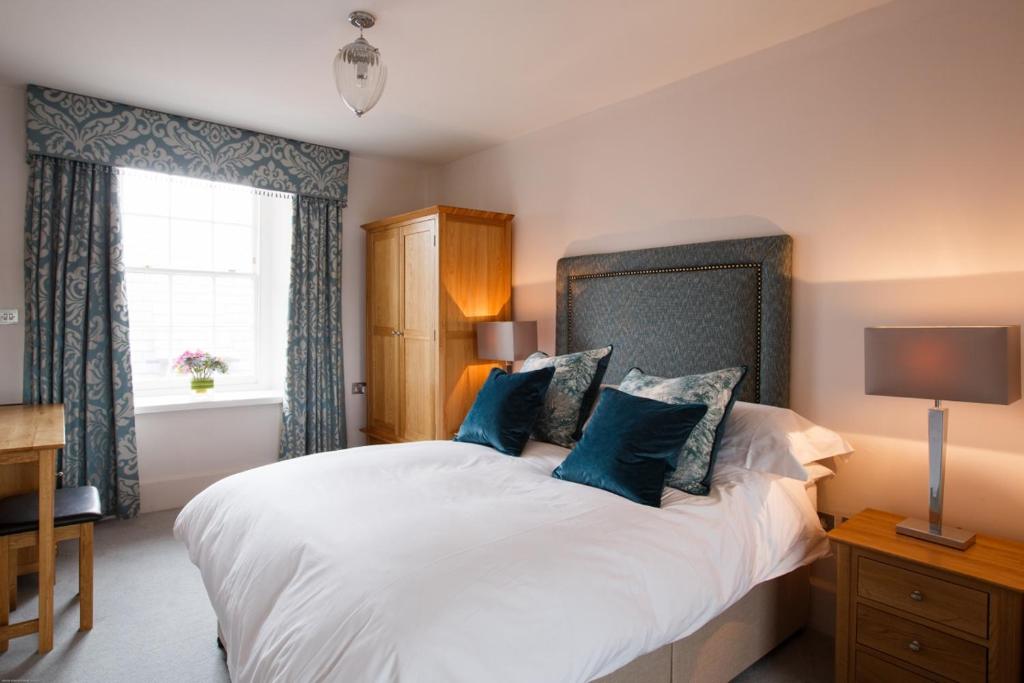 卡迪根Cardigan Castle的卧室配有带蓝色枕头的大型白色床