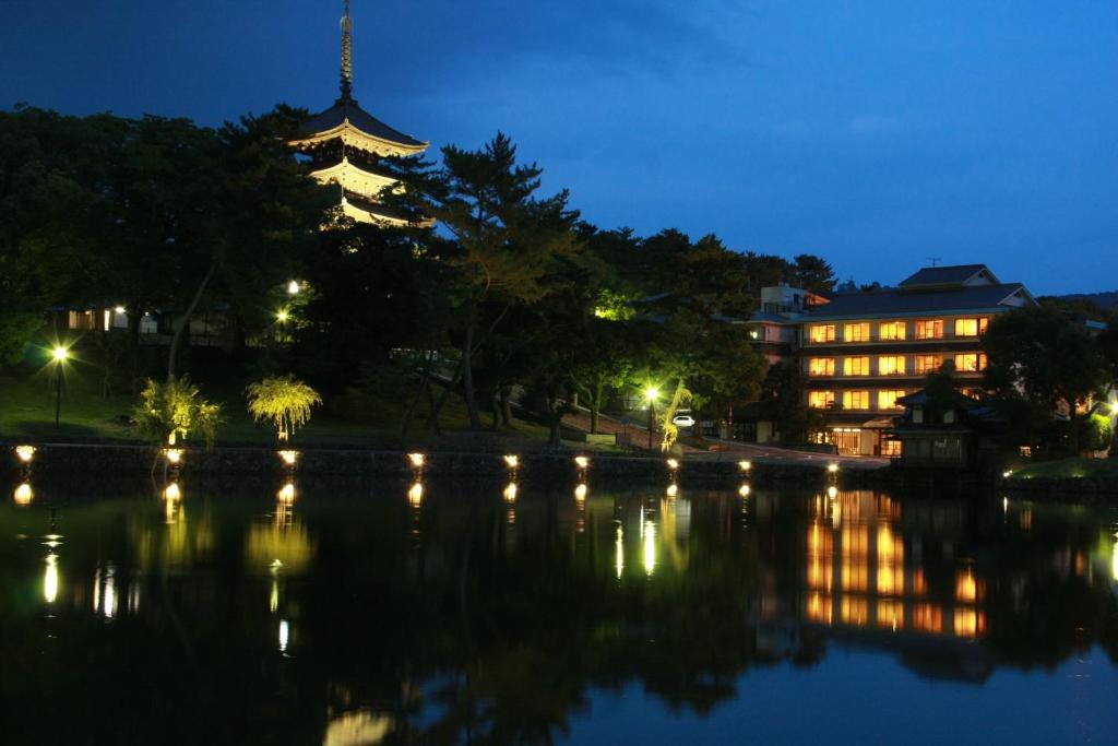 奈良萨若萨瓦吉吉田屋酒店的一座建筑,在晚上有一座塔楼,靠近湖泊
