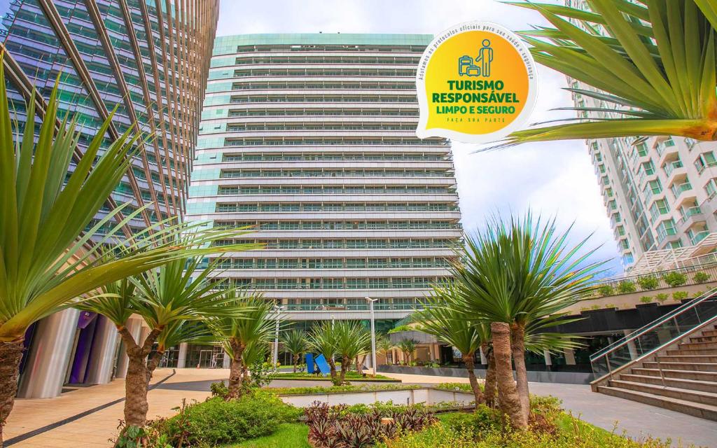 巴西利亚Hplus Vision Executive的棕榈树前有标志的高楼