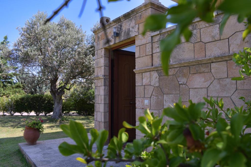KhlóïSeaside "Stone & Light Villa" close to Aegina City的院子里的石头房子,有木门