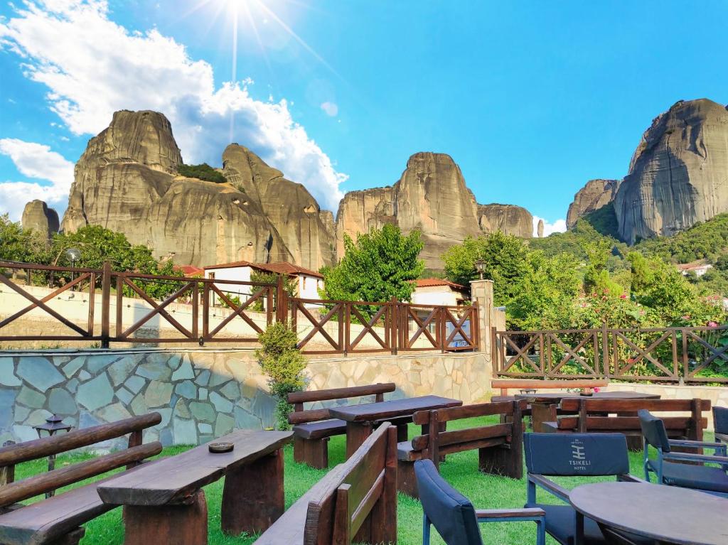 卡兰巴卡Tsikeli Boutique Hotel Meteora - Adults Friendly的餐厅设有木桌、椅子和岩层