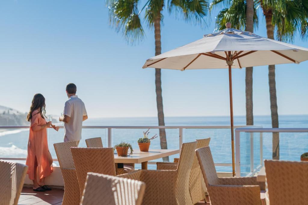 拉古纳海滩Casa Loma Beach Hotel的男人和女人站在一个海景阳台上