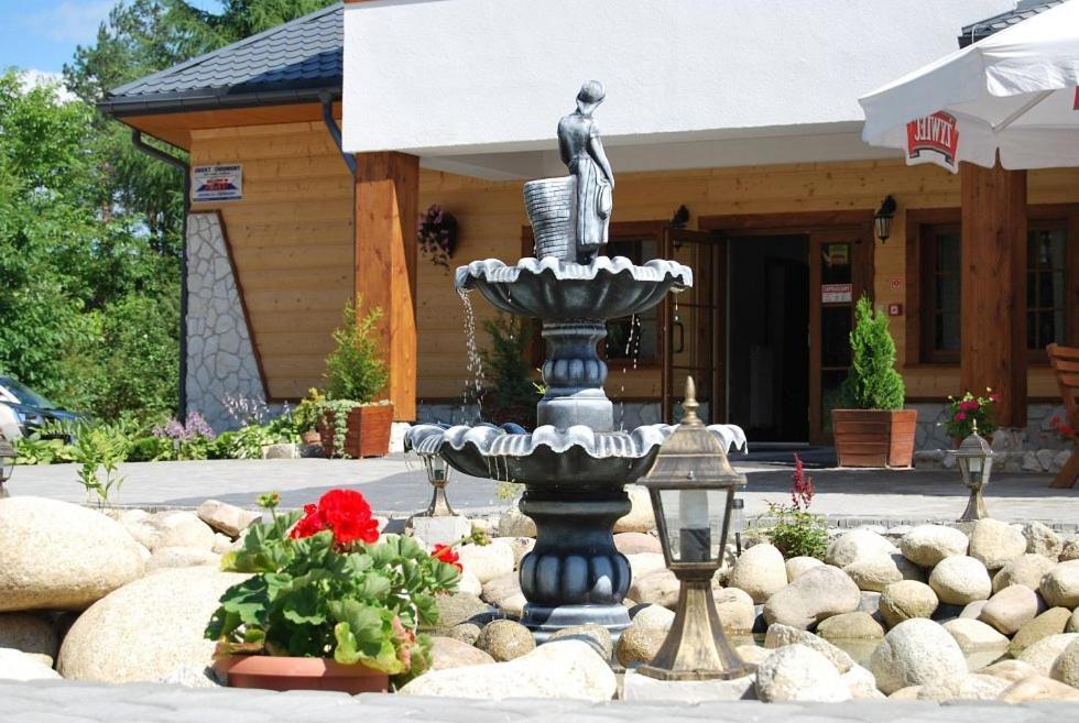 比乌戈拉伊Karczma na Woli的一座有雕像的建筑前的喷泉