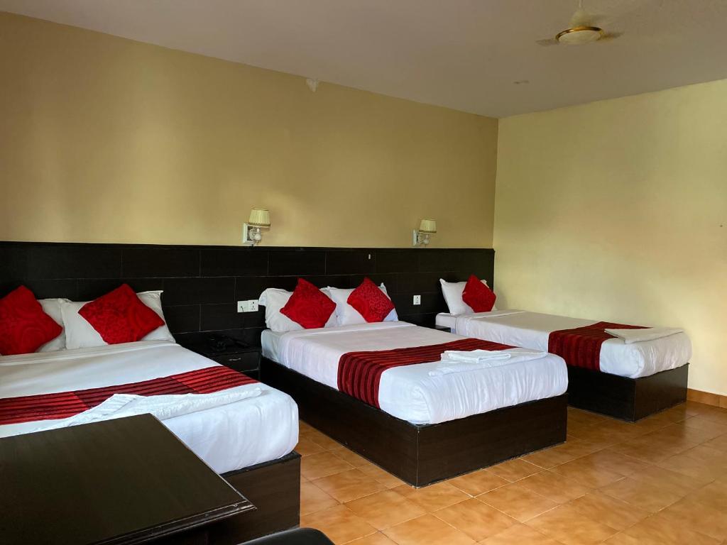 博卡拉Pokhara Cottage的两张位于酒店客房的床铺,配有红色枕头