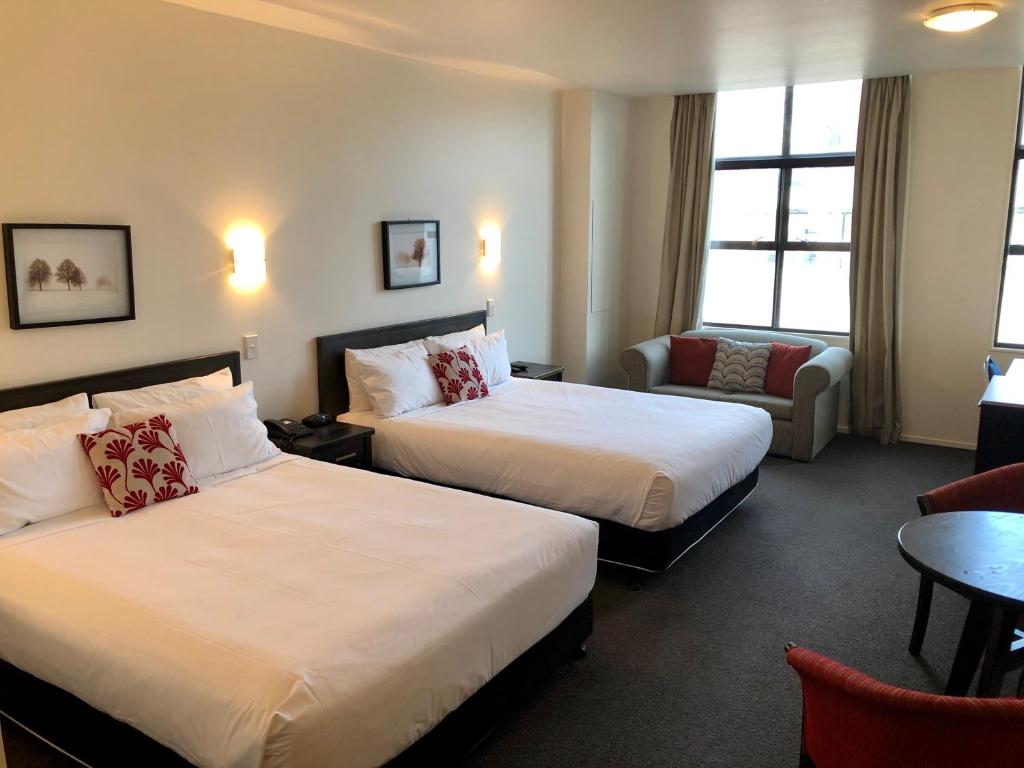 新普利茅斯Distinction New Plymouth Hotel的酒店客房,配有两张床和椅子