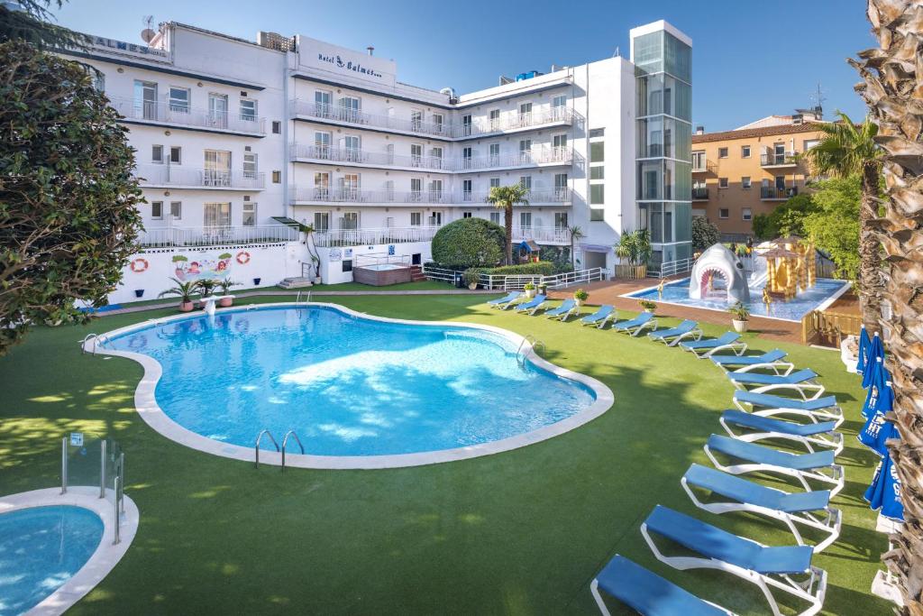卡里拉GHT巴尔梅斯公寓式酒店的大楼前带椅子的大型游泳池