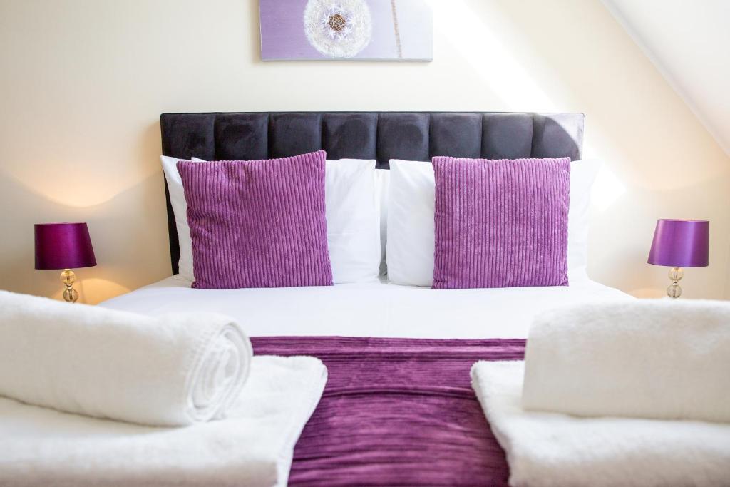 霍兹登Velvet 2-bedroom apartment, Clockhouse, Hoddesdon的一间卧室配有一张大床,提供紫色和白色枕头