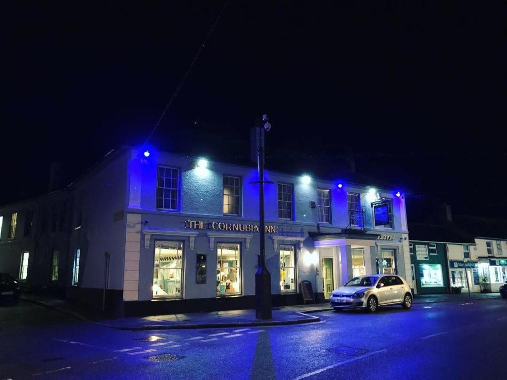 海尔The Cornubia Inn的街上的一座建筑,晚上有蓝色的灯光