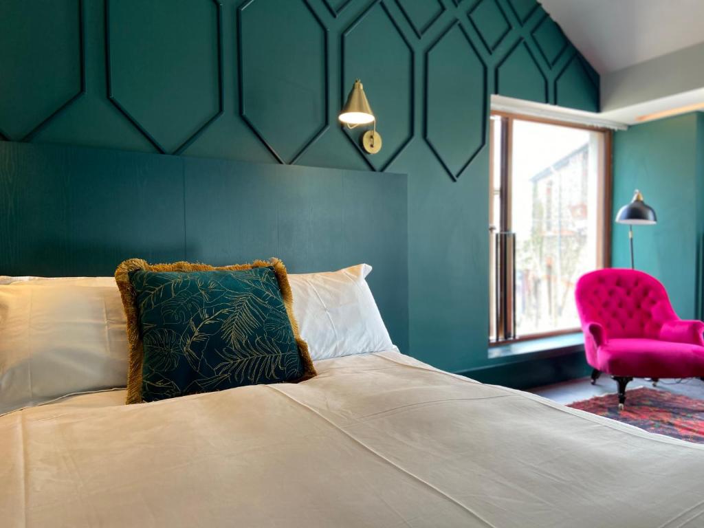基尔代尔The Rooms At Firecastle的一间卧室配有一张床和一张粉红色的椅子