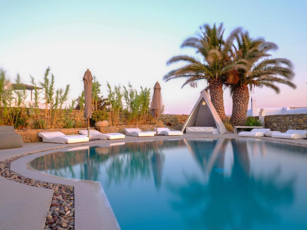 米克诺斯城奥斯特拉可套房酒店的棕榈树和遮阳伞度假村的游泳池