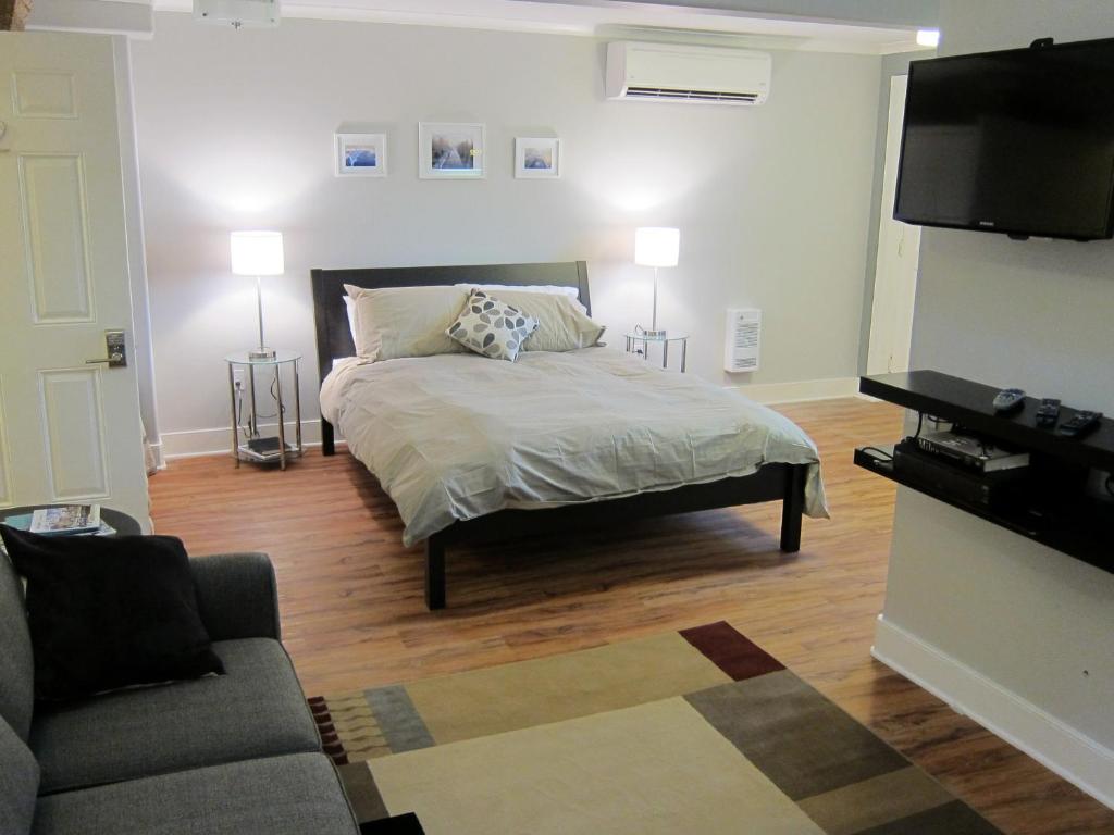MerrickvilleMerrickville Guest Suites的一间卧室配有一张床、一张沙发和一台电视。
