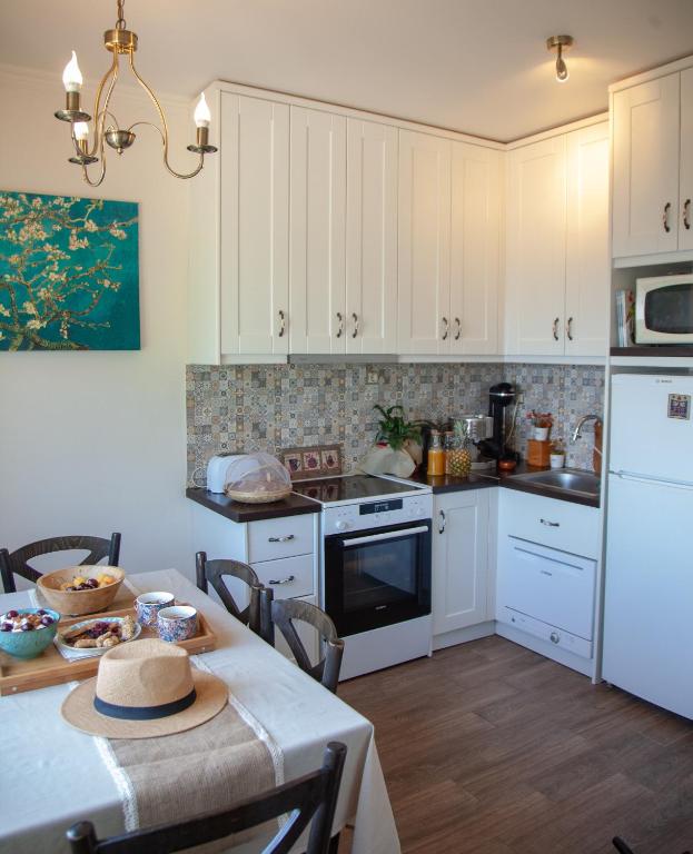 SpartýlasLorantina Luxury Sea View Holiday House close to Barbati &amp; Ipsos Beach with Starlink WiFi的厨房配有白色橱柜和一张带帽子的桌子