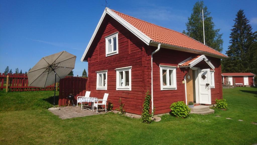 奈舍Barkeryd Norrtorpet的一座红色的小房子,配有桌子和雨伞