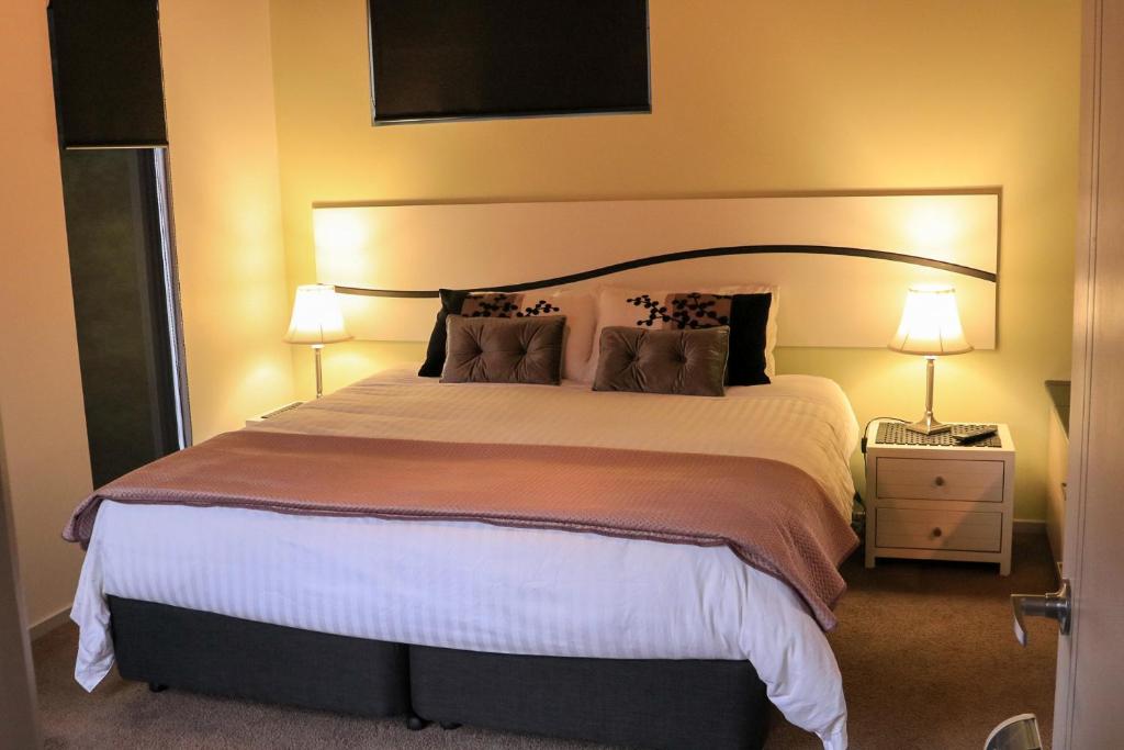 阿尔弗斯通Ulverstone River Retreat的一间卧室配有一张大床和两盏灯