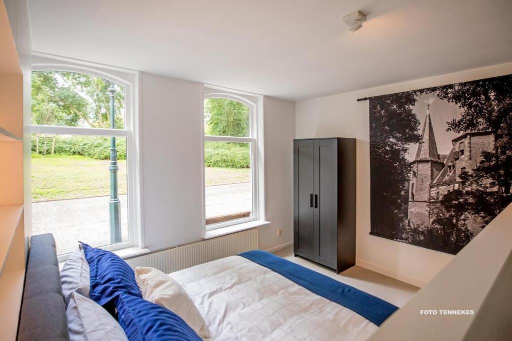 坎彭Bed&Breakfast Tussen de Poorten的一间卧室设有一张床和两个窗户。