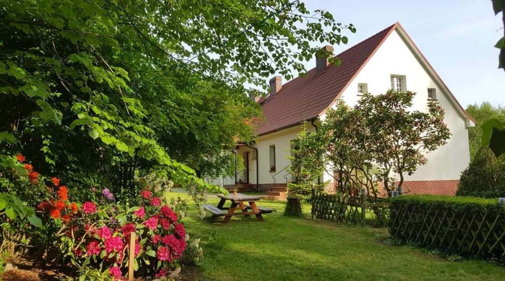 KłodawaAgroturystyka Rębowo的院子里带野餐桌和鲜花的房子