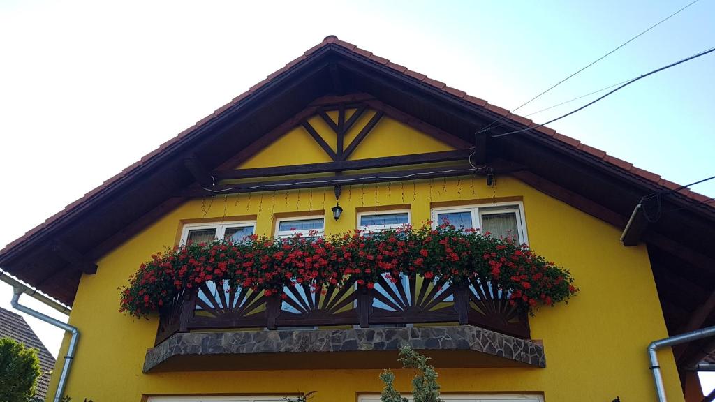 科伦德Hazanéző Panzió的黄色房子,阳台有红色鲜花