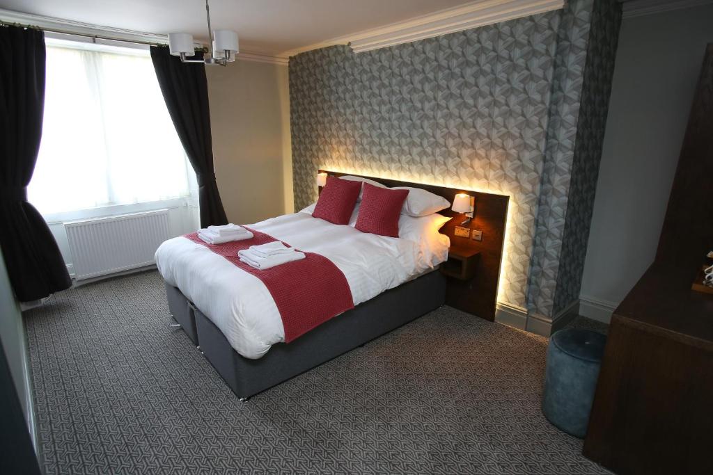 罗斯伯里The Queens Head Hotel的一间卧室配有一张带红色枕头的大床