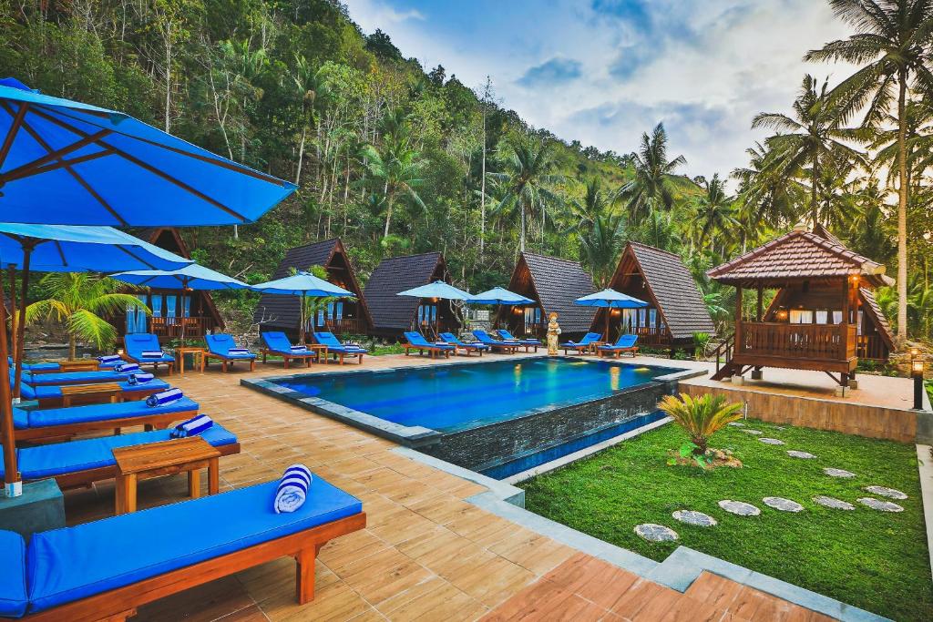 珀尼达岛Mahaloka Valley Nusa Penida的度假村的游泳池,配有蓝色的椅子和遮阳伞