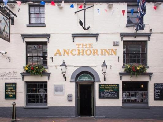 考斯The Anchor Inn的一座白色的建筑,上面有读锚的标志