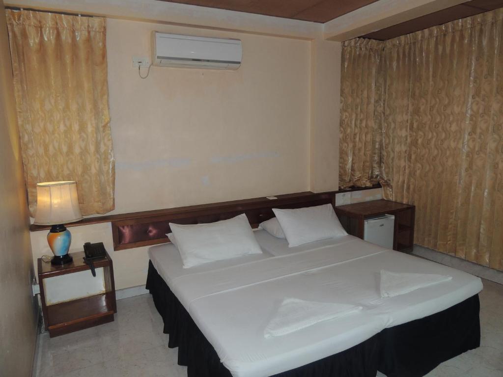 马累关天酒店的卧室设有一张白色大床和一扇窗户。
