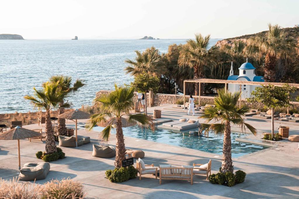 普恩达Seesoo Paros Beachfront Resort的拥有游泳池、棕榈树和海洋的度假胜地