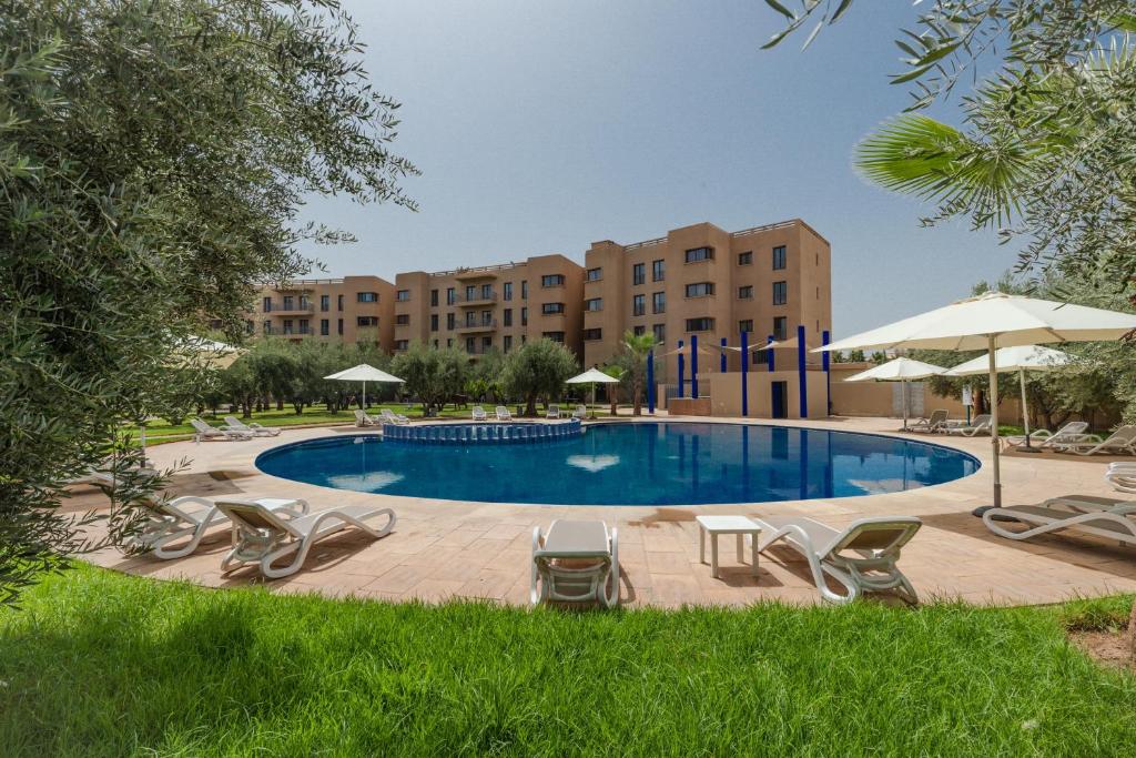 马拉喀什瓦佐公寓酒店 的一个带椅子和遮阳伞的游泳池