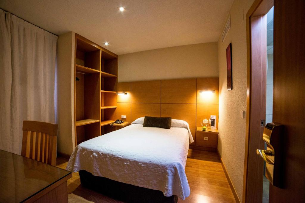 科尔多瓦Hotel Serrano的一间小卧室,配有白色的床和架子