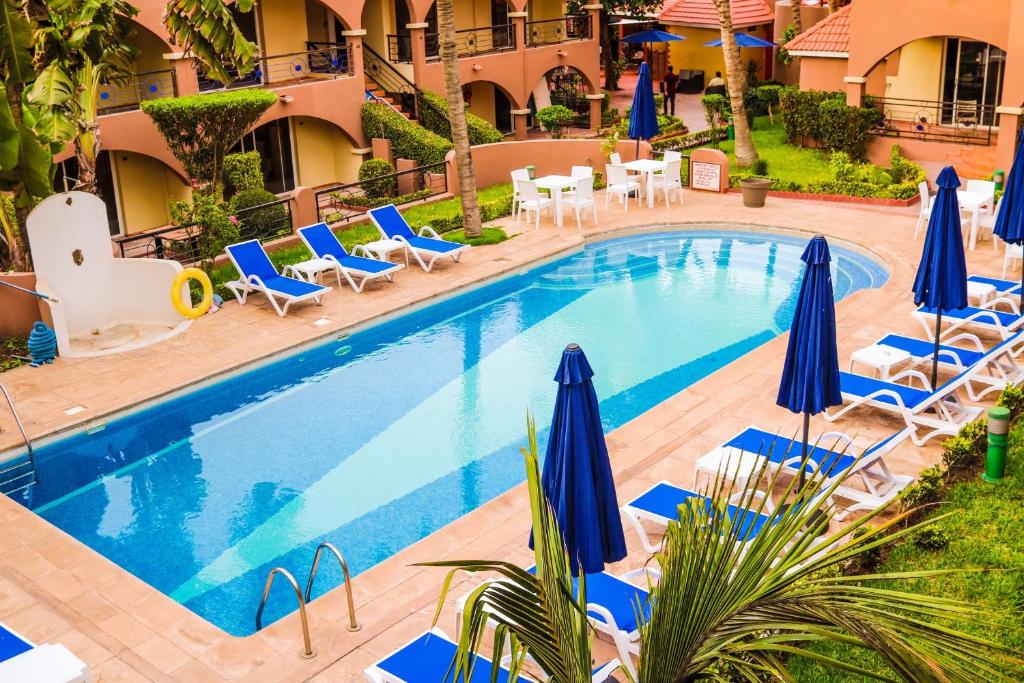 达喀尔Airport Hotel Casino du Cap-vert的一个带蓝伞和躺椅的游泳池